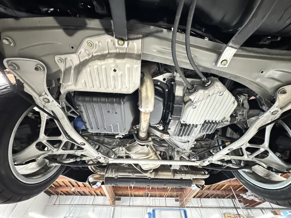 Underbody detail of a 2005 Acura NSX showcasing clean components and exhaust system, emphasizing professional detailing services by Apollo Auto Spa.